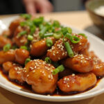 Finished Air Fryer Orange Chicken with sesame seeds and green onions, served with steamed rice.