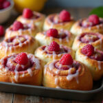 Freshly baked Raspberry Cinnamon Rolls with lemon glaze and raspberries, ready to serve.